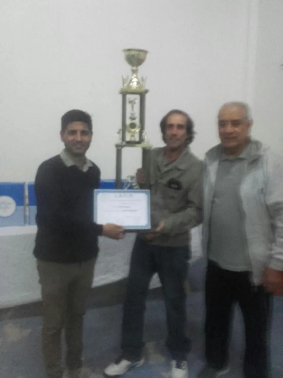 Entrega de la Copa Challenger: tres personas posan con el trofeo y el diploma