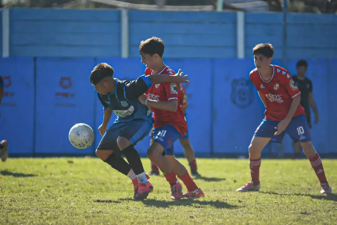 Dos chicos de la categoría infantil disputando la pelota en la cancha del club