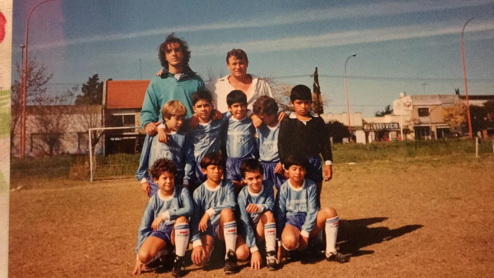 Otro equipo infantil del club posando en la cancha de tierra junto a dos adultos