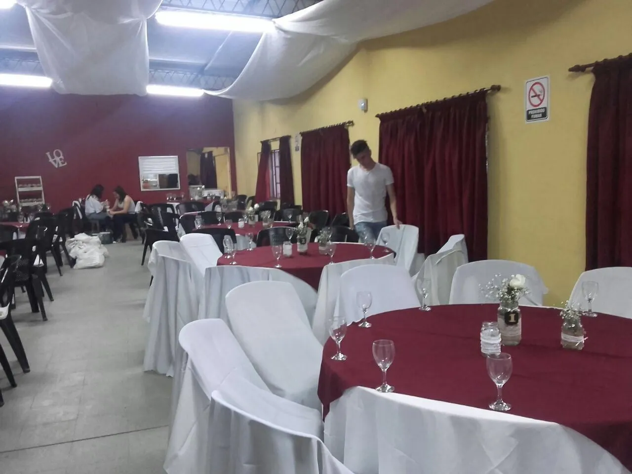 El salón de eventos del club montado con mesas vestidas para una fiesta